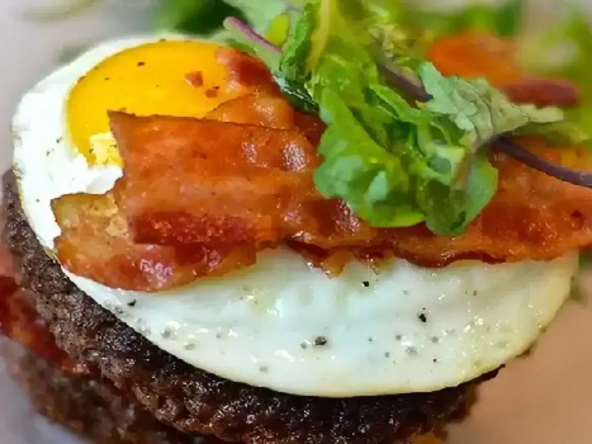 Pyszny burger z wieprzowego mięsa mielonego, jajkiem sadzonym, chrupiącym boczkiem i świeżą sałatką. Idealny przepis na obiad!