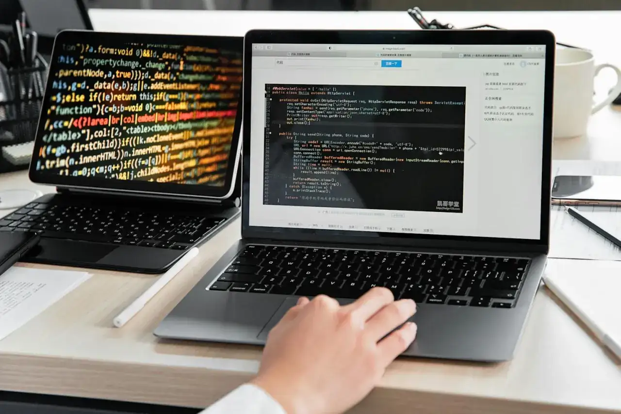Person lernt Programmieren nebenberuflich. Auf dem Laptop wird Code angezeigt, der für eine Umschulung nebenberuflich nützlich ist.