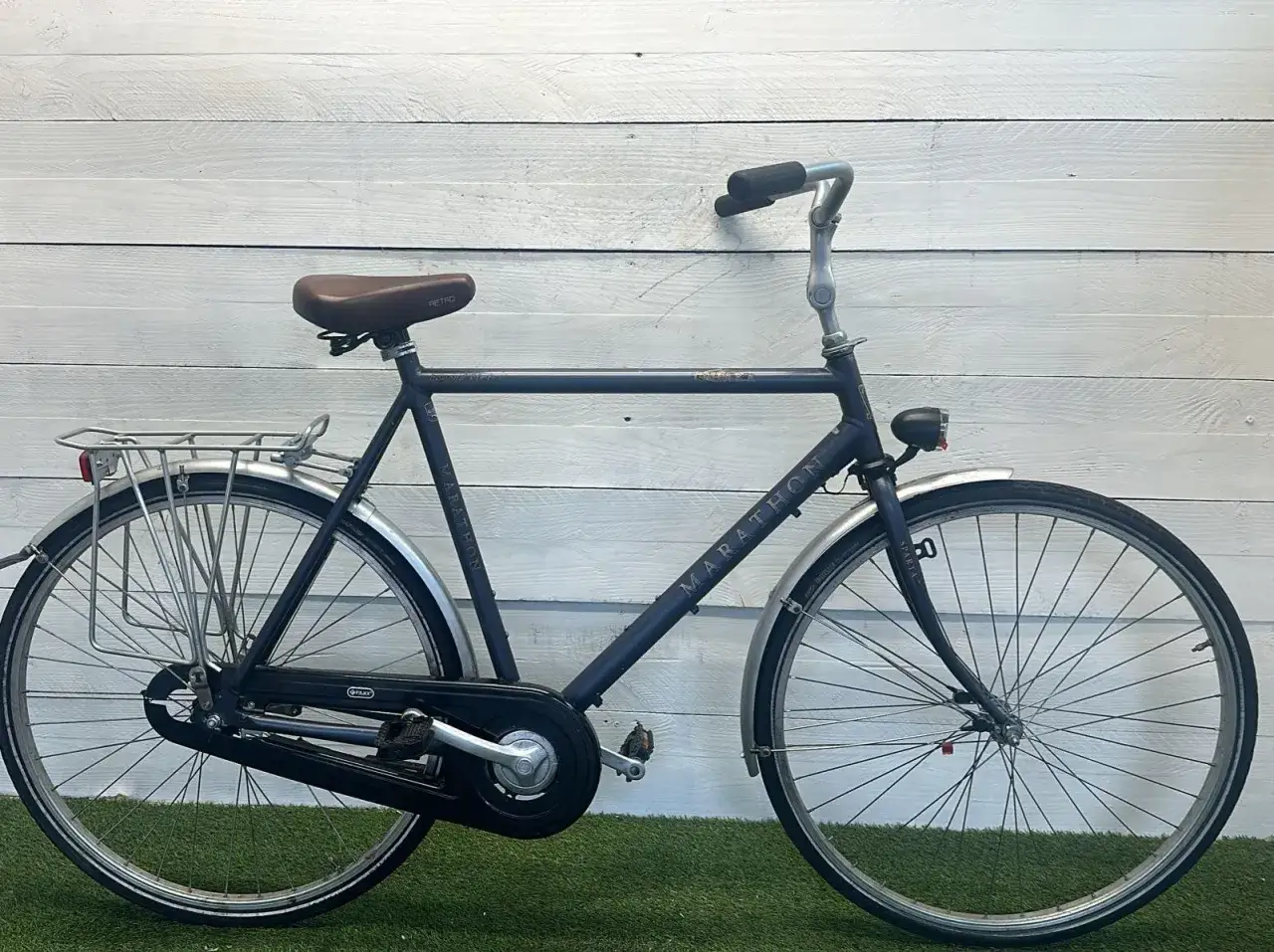 Een donkerblauwe Sparta Marathon, een klassiek model met bruin retro zadel en bagagedrager.