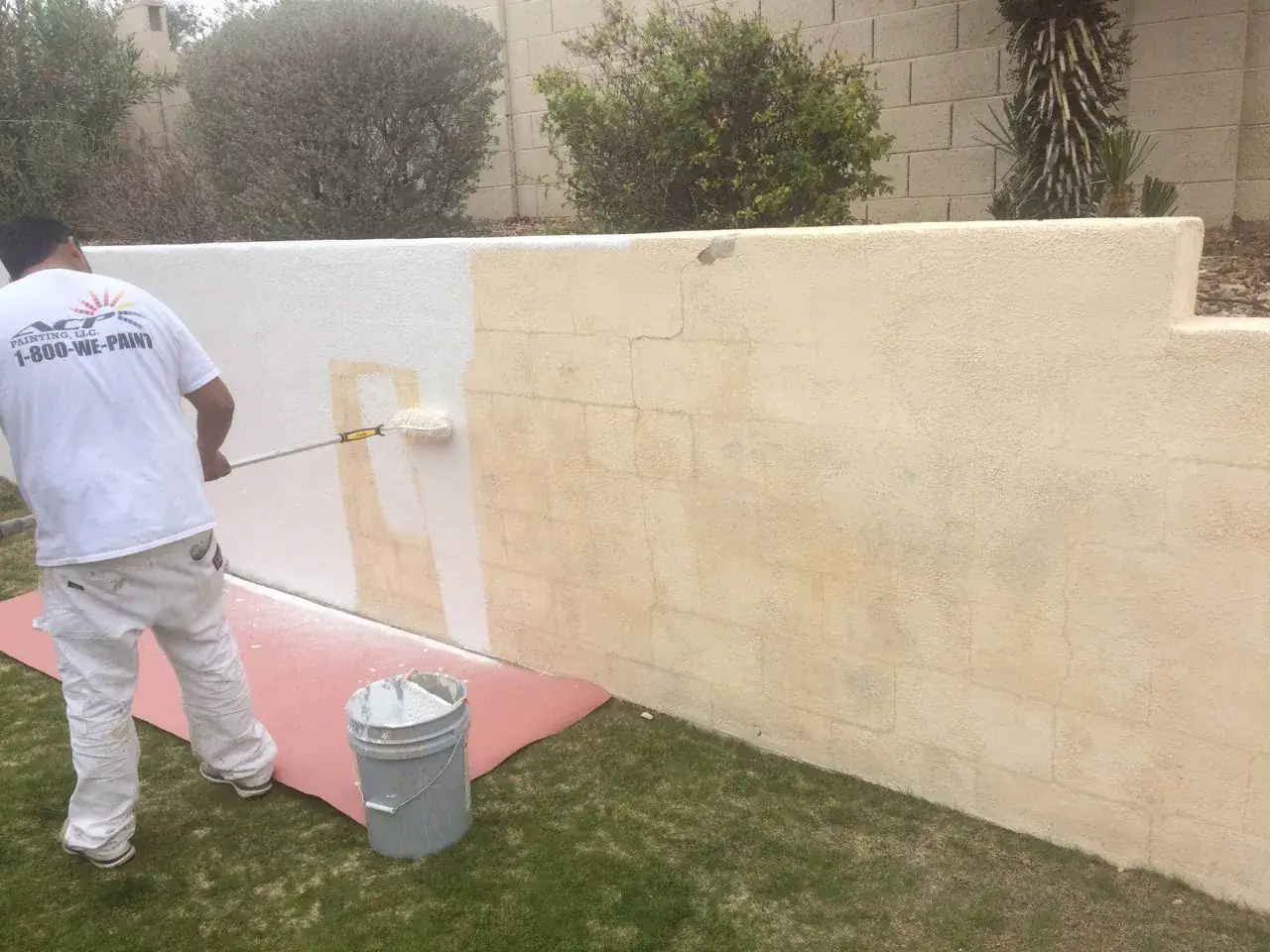 Un pintor aplica una capa de pintura blanca sobre bloques de hormig&oacute;n, transformando la pared.