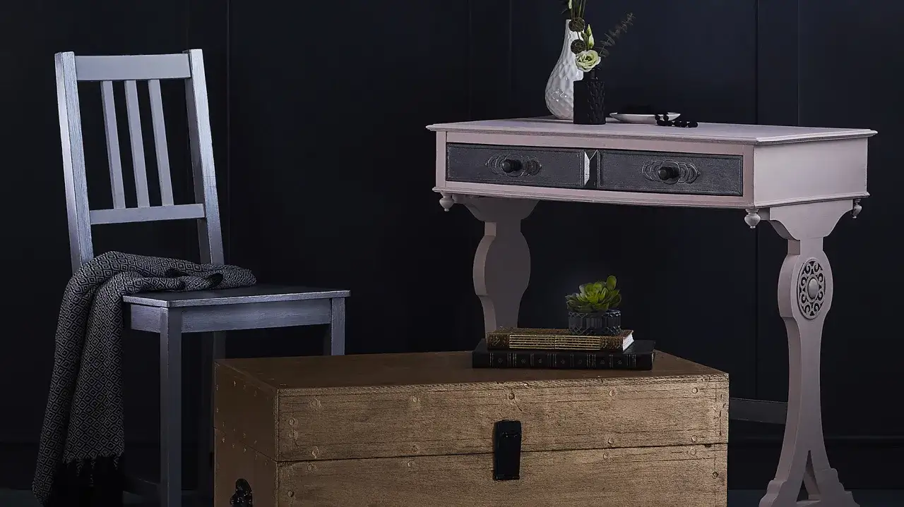 Silla plateada y c&oacute;moda con cajones oscuros, un ba&uacute;l de madera y un jarr&oacute;n. Ideas para saber como lacar un mueble y darle un nuevo look.