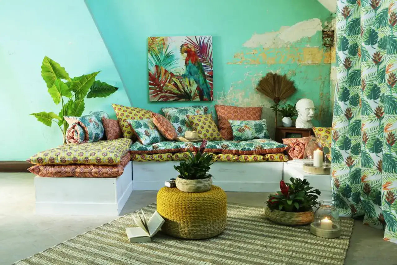 Salon aux couleurs tropicales, inspiration pour une deco antillaise a faire soi meme. Canap&eacute; modulable, coussins aux motifs v&eacute;g&eacute;taux et perroquet.