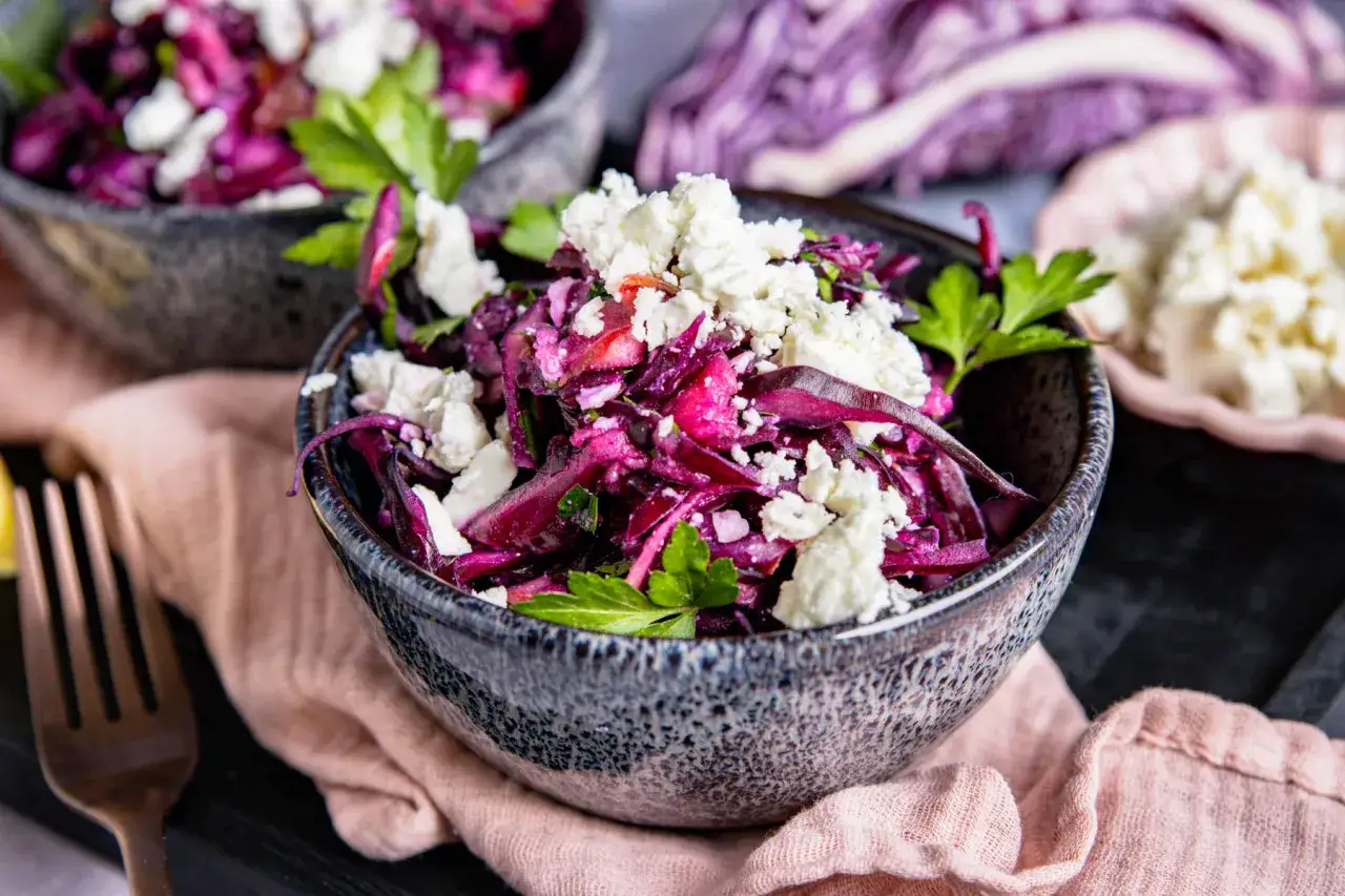 Ein k&ouml;stlicher rotkohlsalat mit feta, garniert mit frischer Petersilie, serviert in einer rustikalen Sch&uuml;ssel.