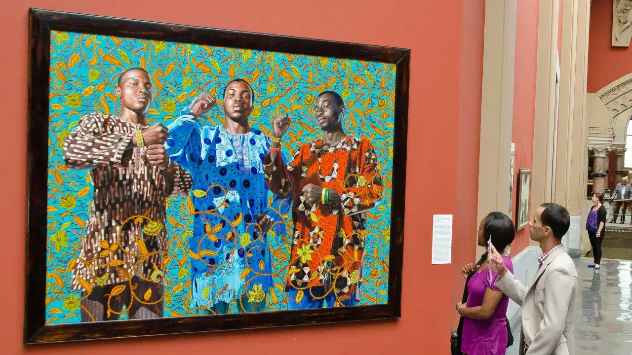 A vibrant painting by a famous black artist depicts three young men in colorful, patterned clothing against a bright blue, floral background.