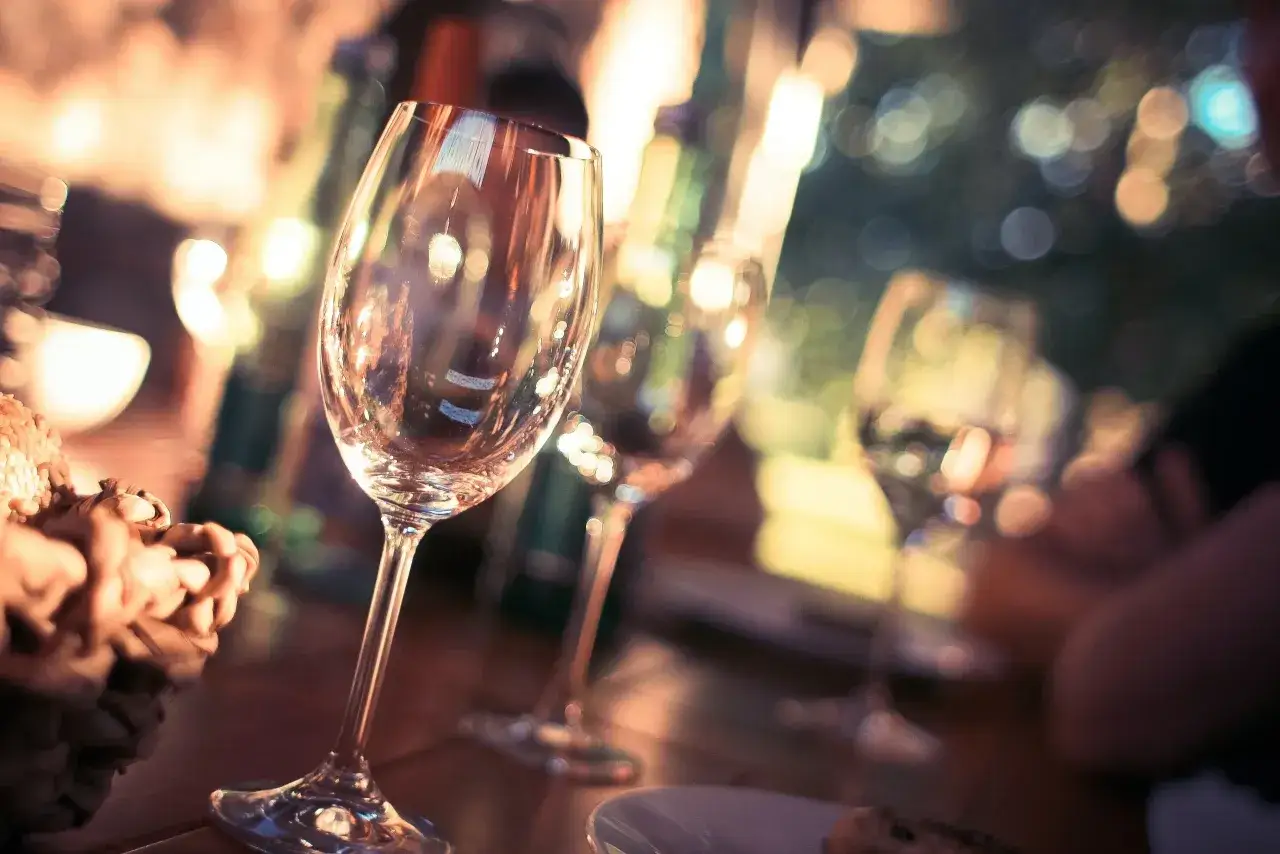 Calici di vino vuoti su un tavolo, con luci sfocate sullo sfondo. Attenzione: il vino contiene nichel.