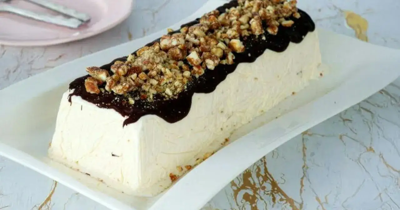 Un delizioso parfait di mandorle, ricoperto di cioccolato fuso e granella croccante, pronto per essere gustato.