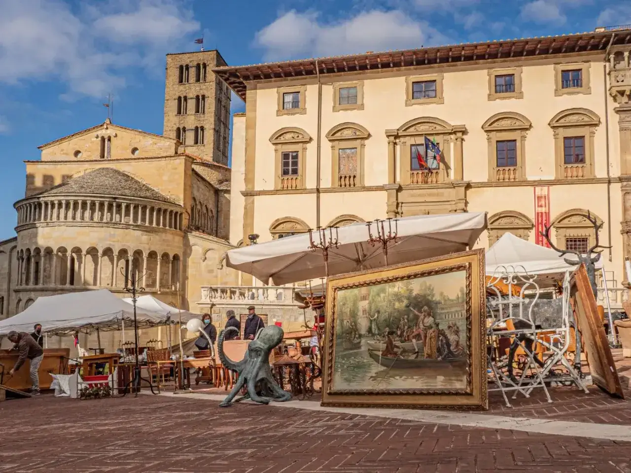 Mercato dell'antiquariato in Piazza Grande, Arezzo cosa vedere: opere d'arte, sculture e arredi antichi davanti a palazzi storici.
