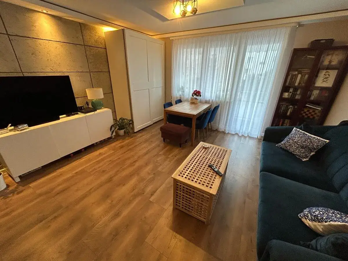 Przytulny salon z jadalnią, idealny na relaks. Wygodna kanapa, stolik kawowy i st&oacute;ł z krzesłami. Atrium Radogoszcz - miejsce, gdzie czujesz się jak w domu.