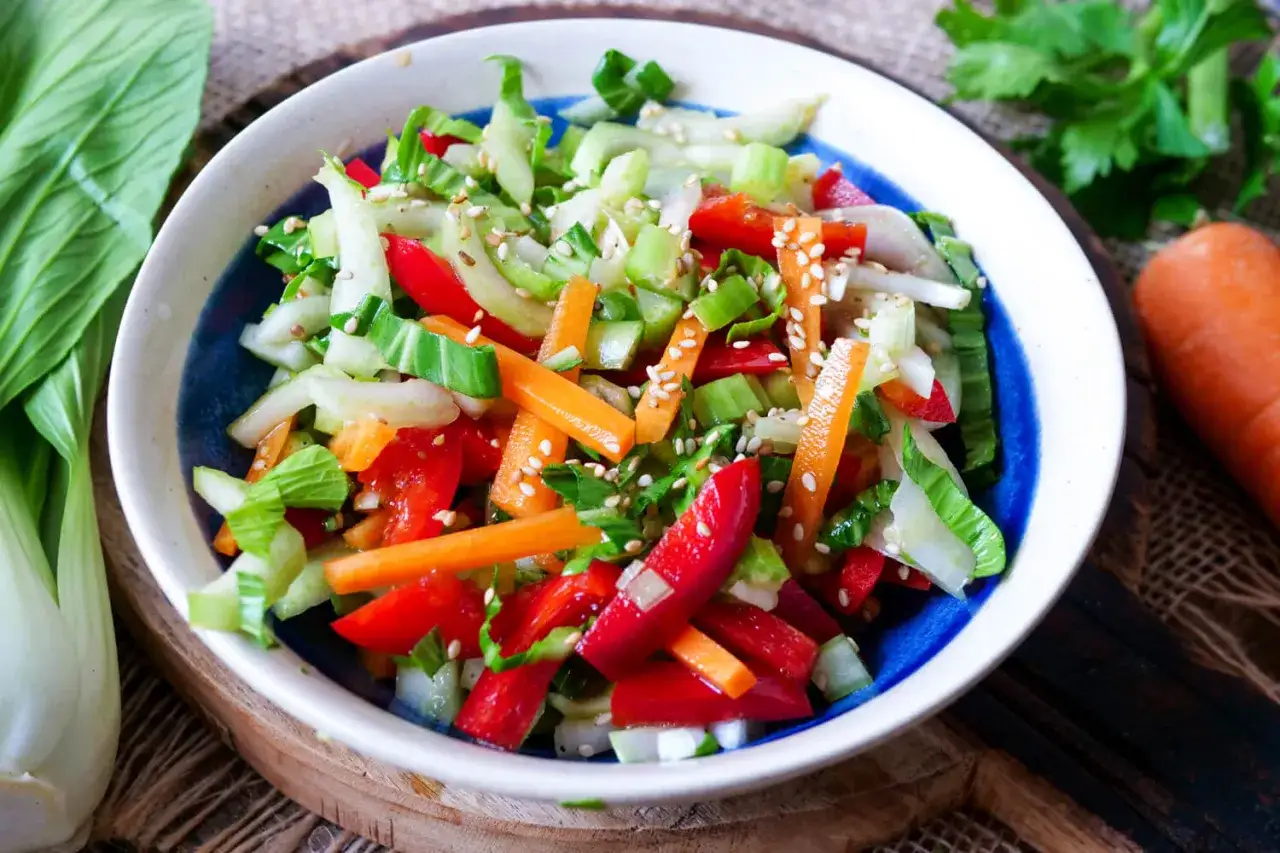 Bunter Salat mit Paprika, Karotten und Gurke, garniert mit Sesam. Eine frische Idee, um pak choi roh essen zu genießen.