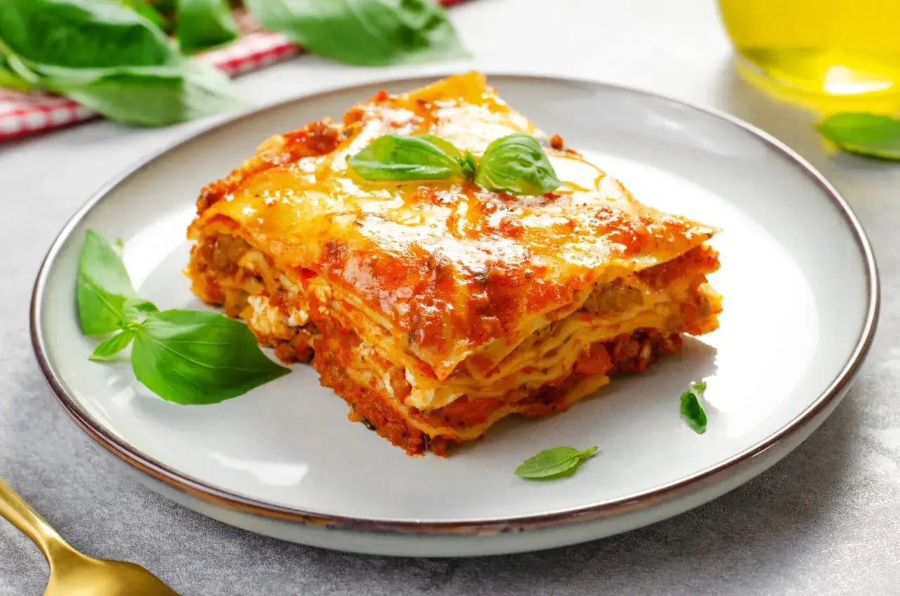 Une part de lasagne g&eacute;n&eacute;reuse, garnie de basilic frais. Une invitation &agrave; d&eacute;couvrir cette recette de lasagne r&eacute;confortante.