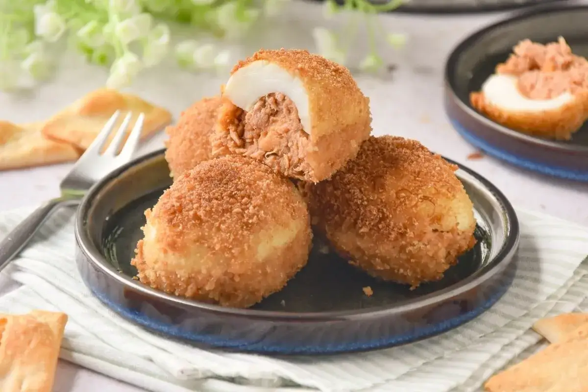 Deliciosos huevos rellenos rebozados, crujientes por fuera y jugosos por dentro, servidos en un plato con galletas.