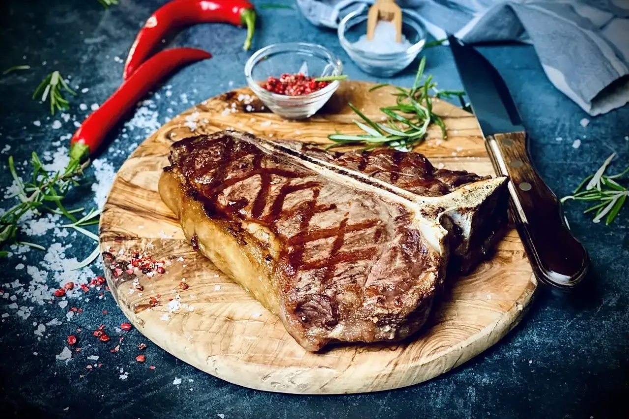 Perfekt gegrilltes T-Bone-Steak, bereit f&uuml;r die t-bone steak zubereitung. Mit Rosmarin, Chili und grobem Salz garniert.