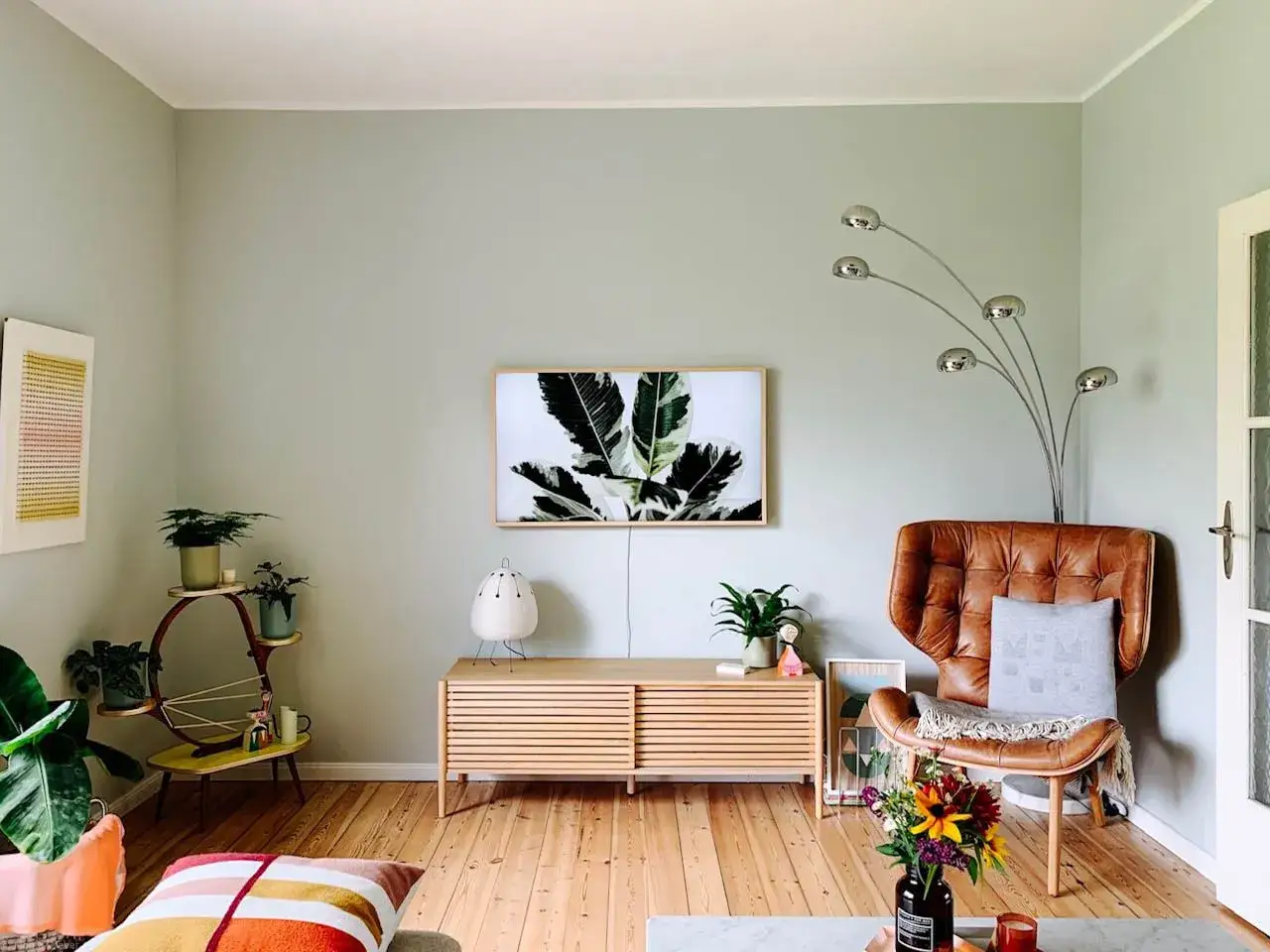 Gem&uuml;tliches Wohnzimmer mit mint farbener Wand, braunem Ledersessel und vielen Pflanzen.