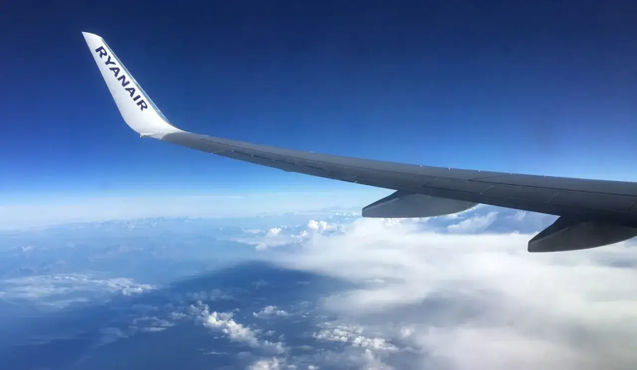 Skrzydło samolotu Ryanair nad chmurami, zapowiedź bezpośrednich lot&oacute;w do Barcelony z Polski.