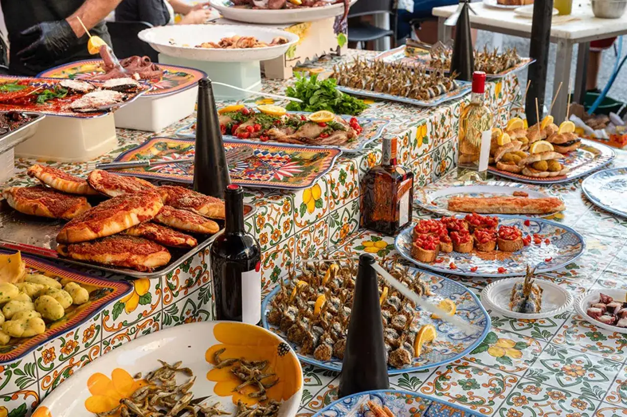 Un banchetto di street food siciliano: pizze, pesce fritto, bruschette e polpo, un tripudio di sapori mediterranei.