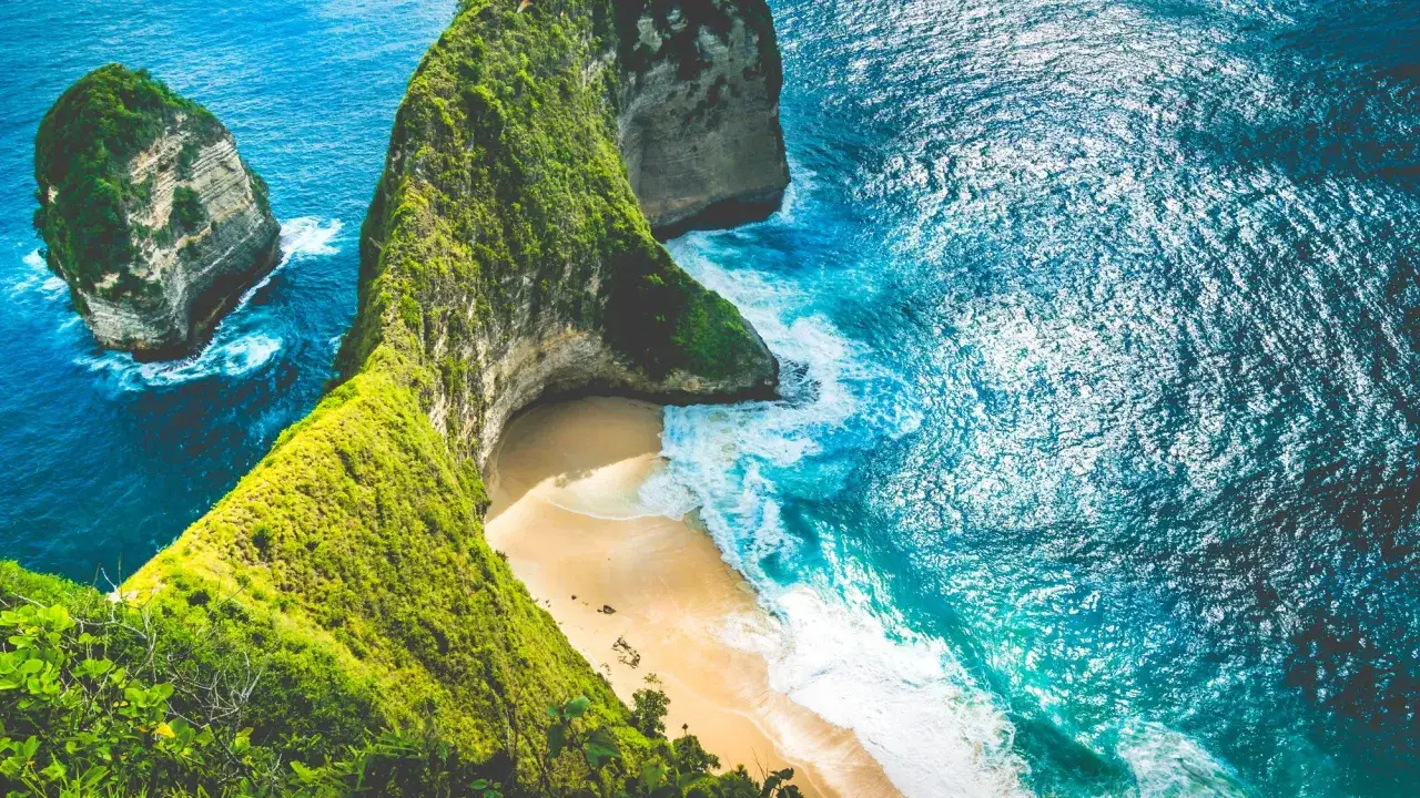 Widok na klify i plażę na Bali. Marzysz o podróży? Sprawdź, ile trwa lot na Bali z Polski.