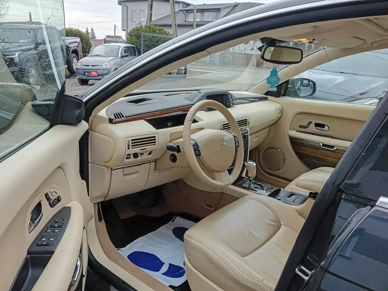 Wnętrze Citroëna C6 z beżową skórzaną tapicerką i drewnianymi wstawkami. Widok na deskę rozdzielczą, kierownicę i fotele.