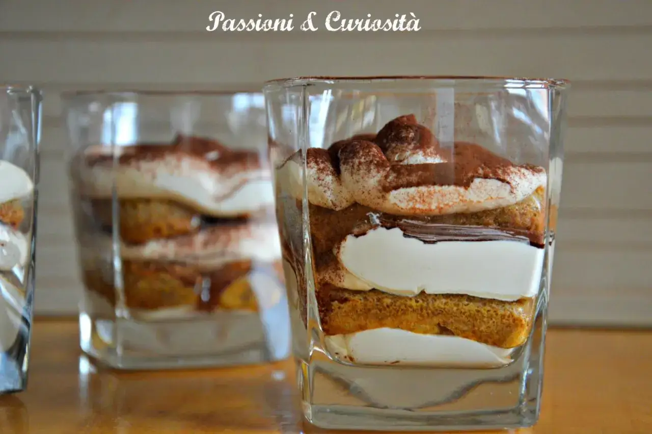 Tiramisù con philadelphia in bicchiere, strati di savoiardi, crema e cacao.