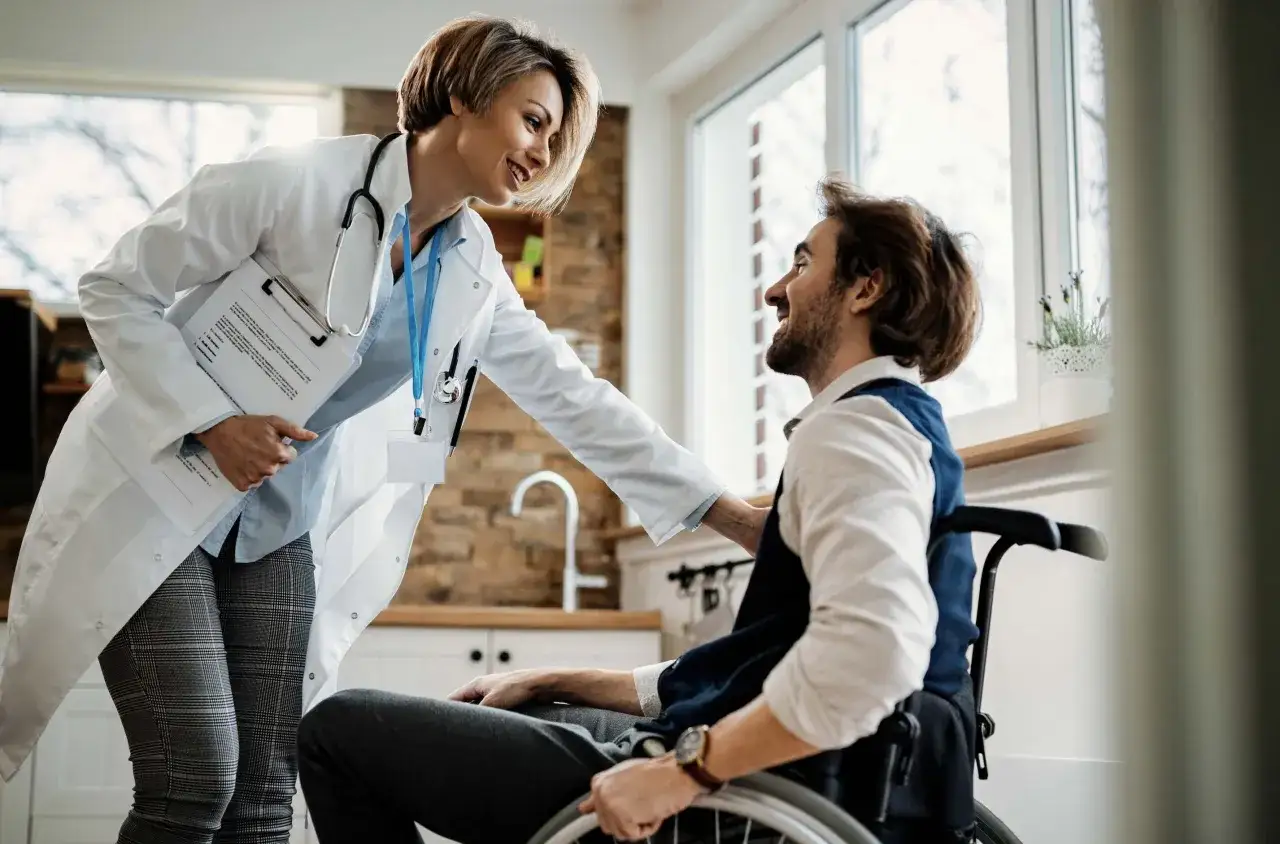 Medico sorridente parla con un paziente su sedia a rotelle, con un camice bianco e stetoscopio. L'appuntamento del 18/80 è andato bene.