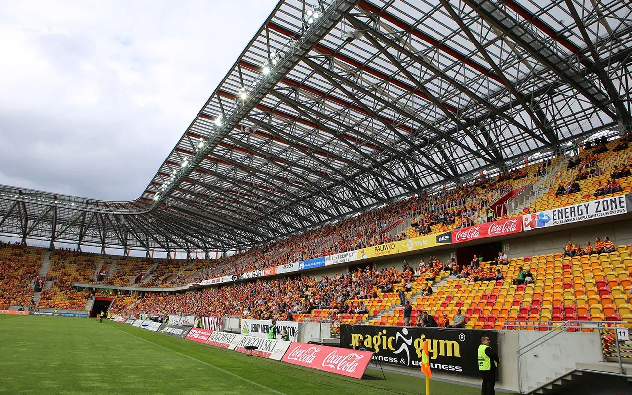 Widownia stadionu podczas meczu Bruk-Bet Termalica – Jagiellonia Białystok. Kolorowe trybuny wypełnione kibicami.