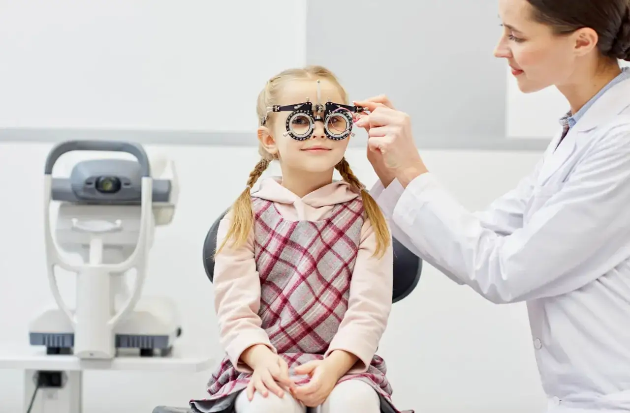 Mała dziewczynka z warkoczami podczas badania wzroku. Optometrysta sprawdza, czy wada wzroku minus może się cofnąć.