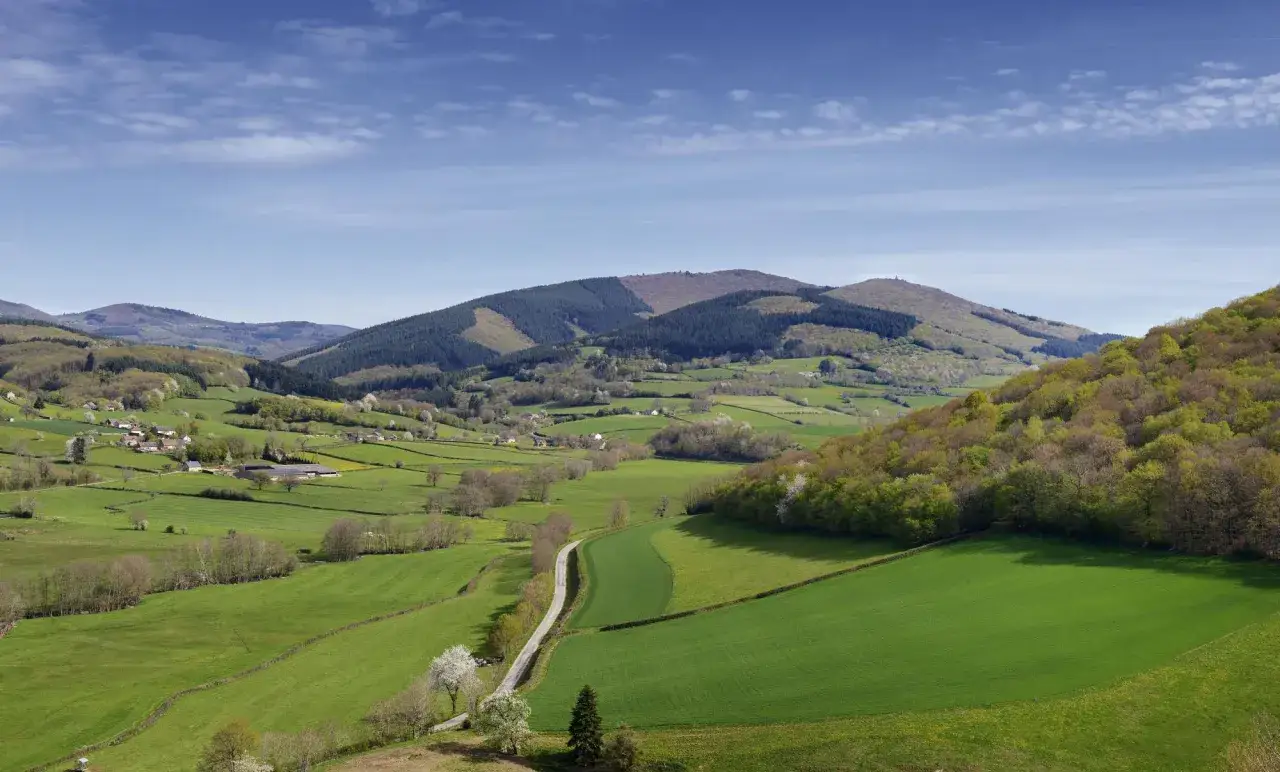 Paysages verdoyants du Morvan, parfaits pour un séjour de trois jours. Vallées, collines boisées et petits hameaux sous un ciel bleu.