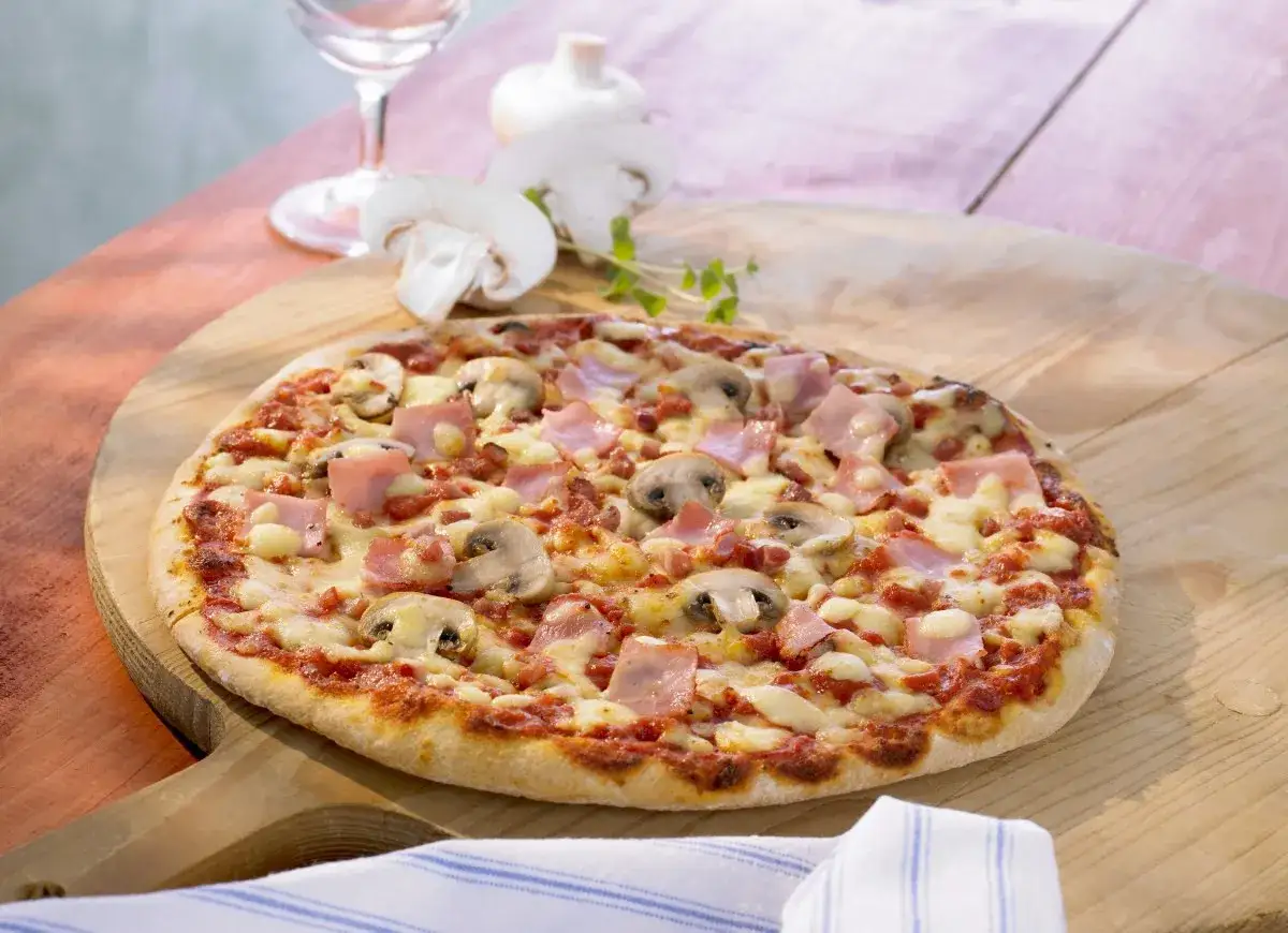 Pizza z pieczarkami i kawałkami szynki, idealna na szybki obiad. Jaka szynka na pizzę? Ta wygląda pysznie!