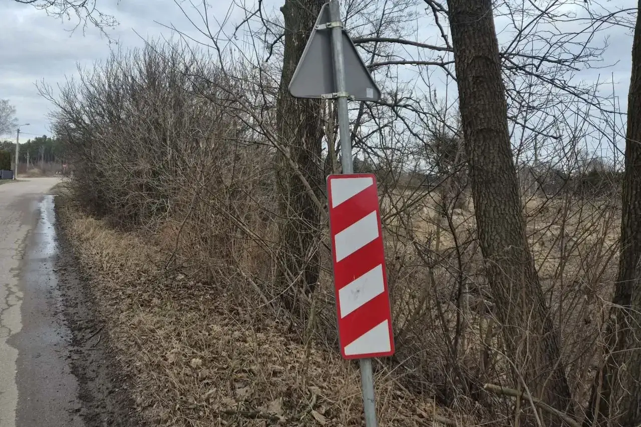 Ostrzeżenie przed przejazdem kolejowym. Znak drogowy z czerwono-białymi pasami wskazuje niebezpieczne miejsce, gdzie mógł nastąpić wypadek przejazd kolejowy.