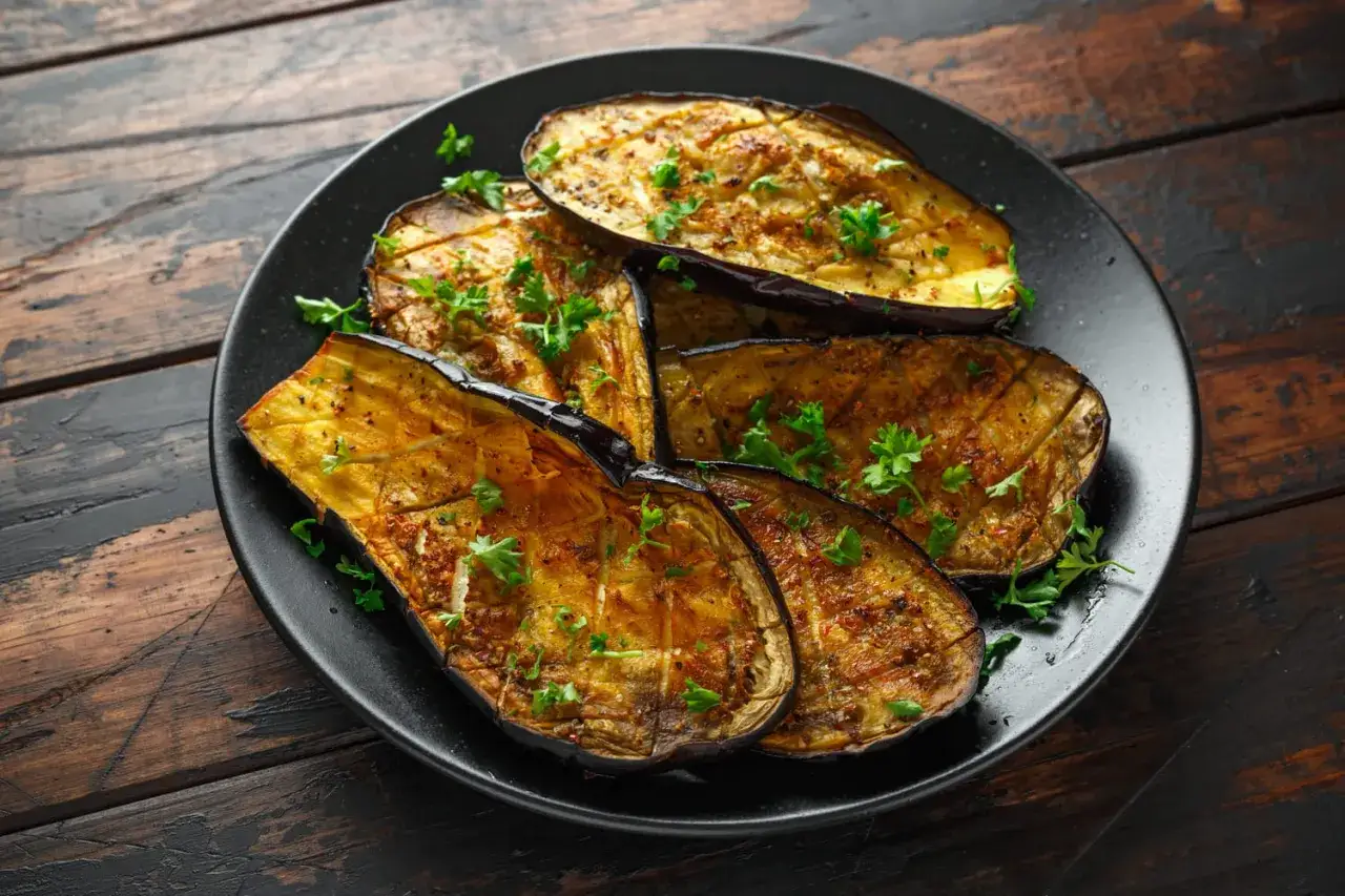 Aubergines grillées, garnies de persil frais, parfaites pour une recette avec aubergine.