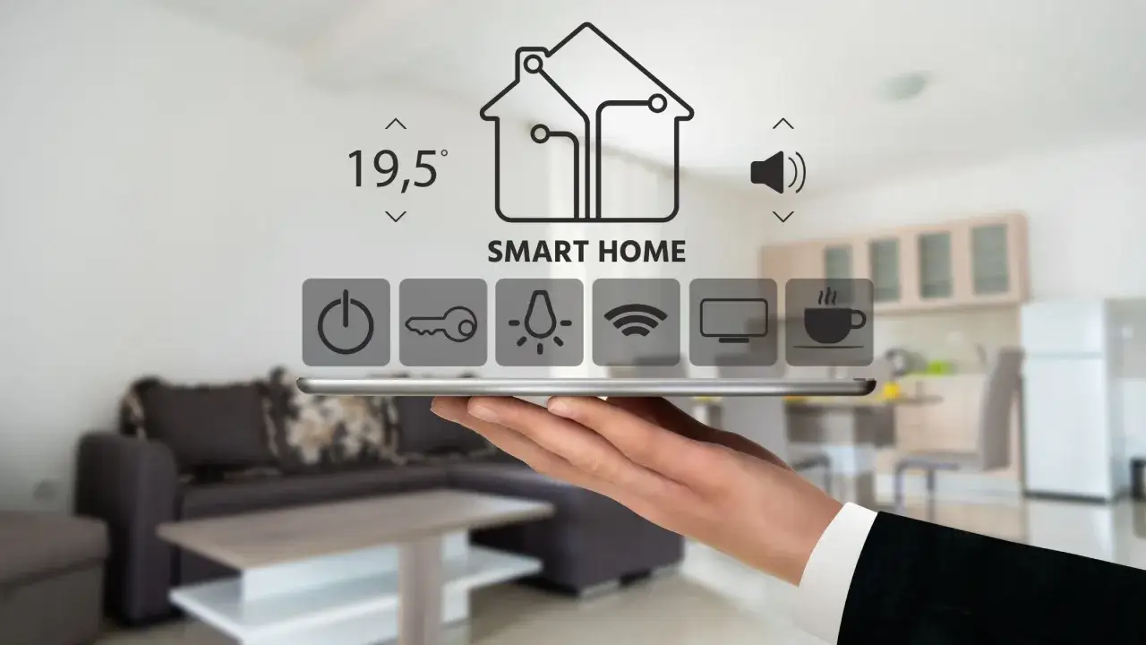 Dłoń trzyma tablet z ikonami smart home, pokazującymi kontrolę nad domem i jego efektywność energetyczną.