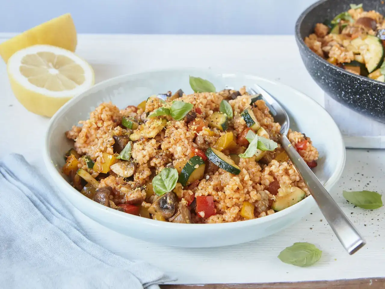 Herzhaftes Gericht mit bulgur oder couscous, Gem&uuml;se und frischem Basilikum, garniert mit Zitronenschale.