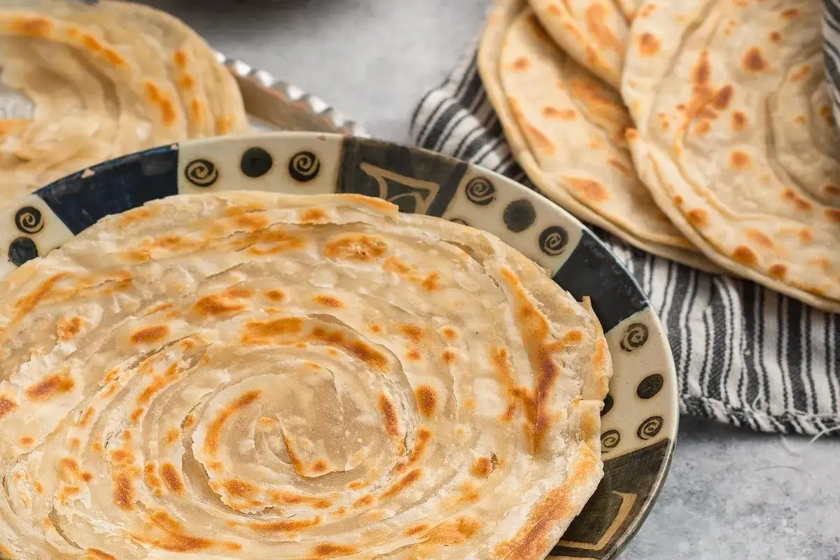 Crescia marchigiana dorata e sfogliata, servita su un piatto decorato.