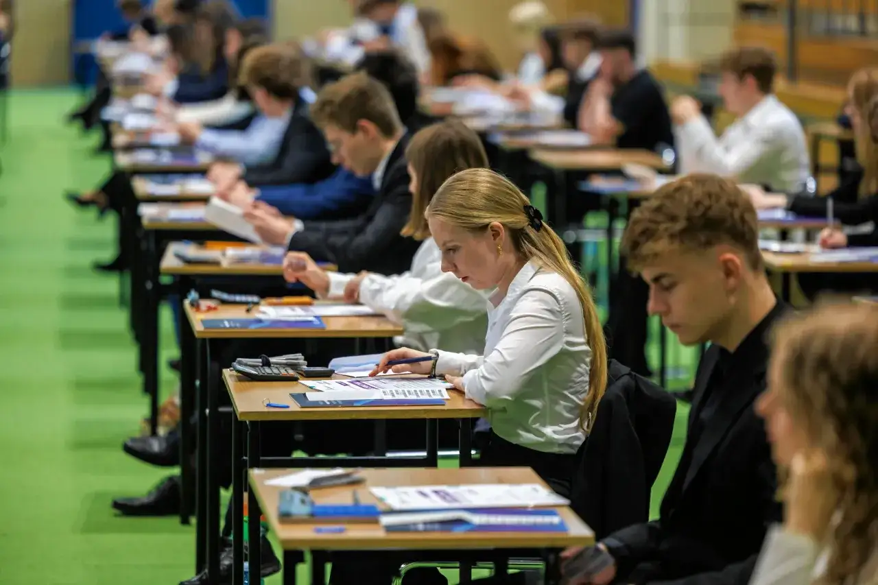 Uczniowie piszą egzamin zawodowy praktyczny. Widać skupienie na twarzach, jak oceniany jest ich trud.