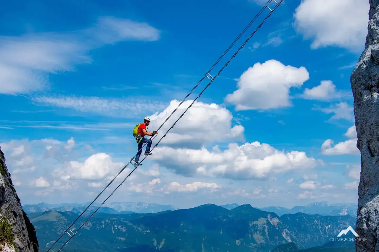 Wspinacz pokonuje drabinę na via ferracie w Dolomitach, podziwiając zapierający dech w piersiach widok na góry.