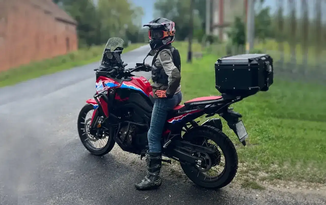 Motocyklista w kasku i z kufrem na bagażniku gotowy na przygodę. Kaszuby motocyklem czekają!