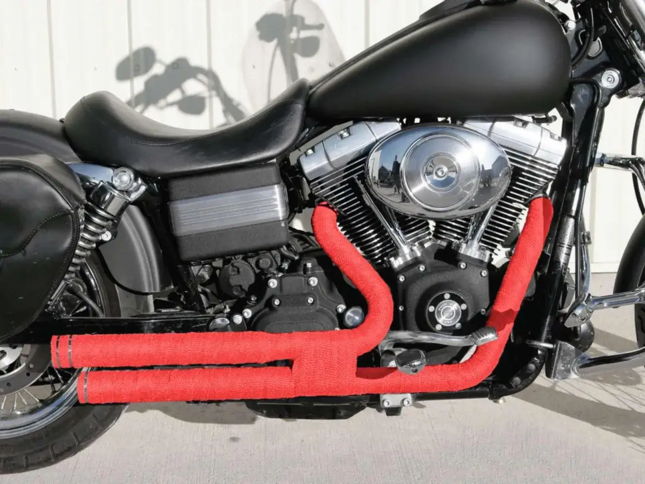 Scarico di una moto custom con fascia termica rossa per un look audace e prestazioni migliorate.
