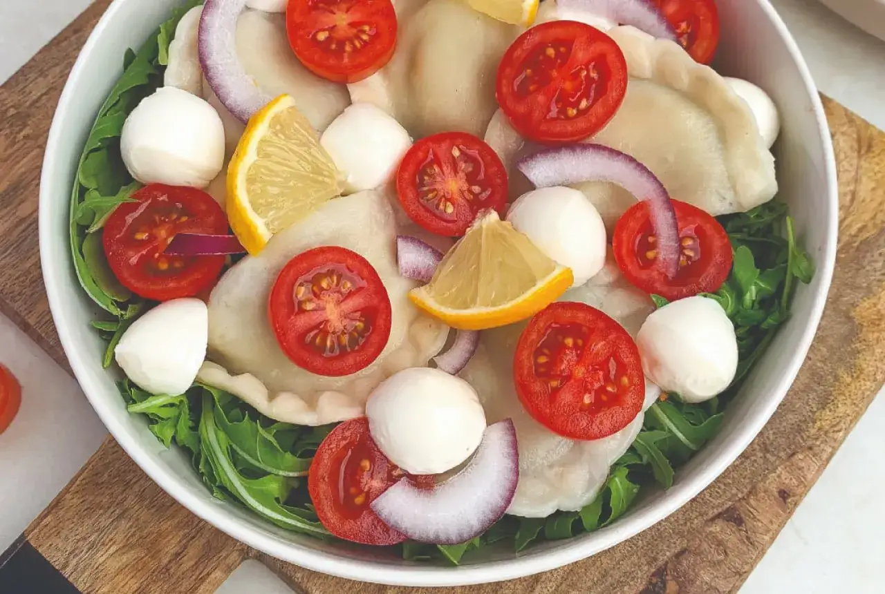 Pierogi ze szpinakiem podane z rukolą, pomidorkami koktajlowymi, mozzarellą, czerwoną cebulą i cytryną. Idealne na lekki obiad.