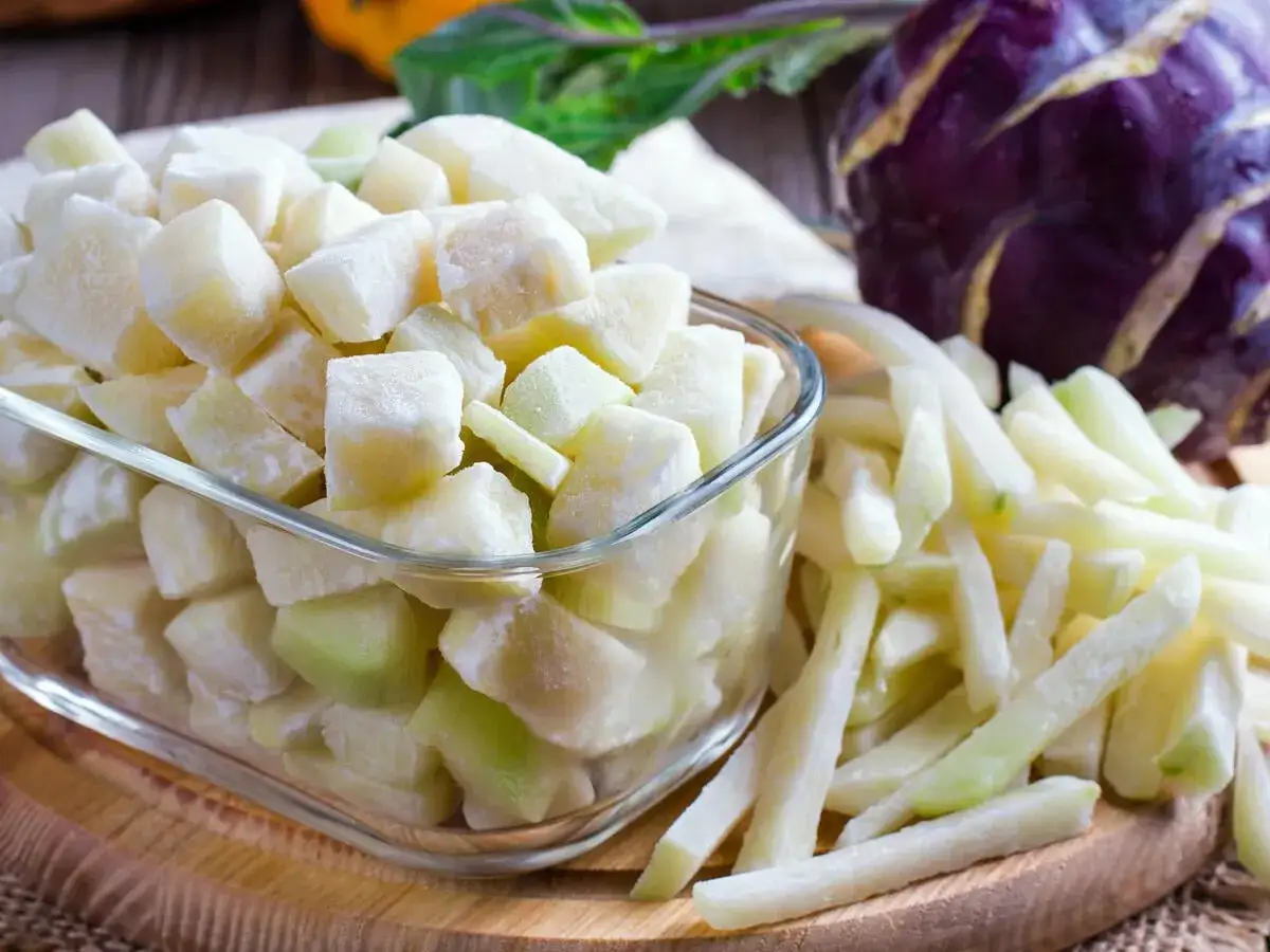 Gefrorene Kohlrabi-Würfel und -Stifte in einer Schüssel und daneben. Perfekt für die Lagerung, um Kohlrabi einfrieren zu können.