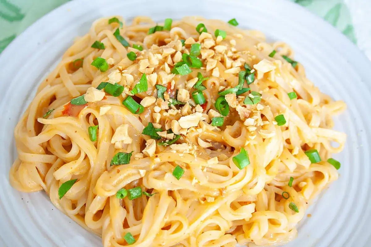 En portion kr&auml;mig pad thai med nudlar, toppad med hackade jordn&ouml;tter och salladsl&ouml;k.