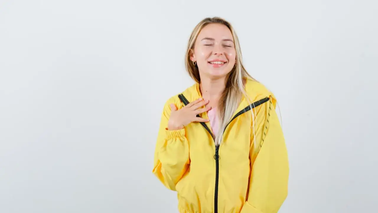 Uśmiechnięta blondynka w żółtej kurtce softshell. Dowiedz się, jak prać softshell, by zachował swoje właściwości.