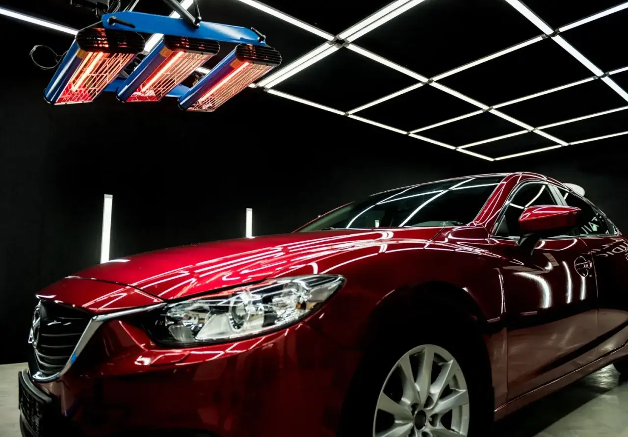 Czerwone, lśniące włoskie auto sportowe pod lampami na podczerwień w studio detailingowym.