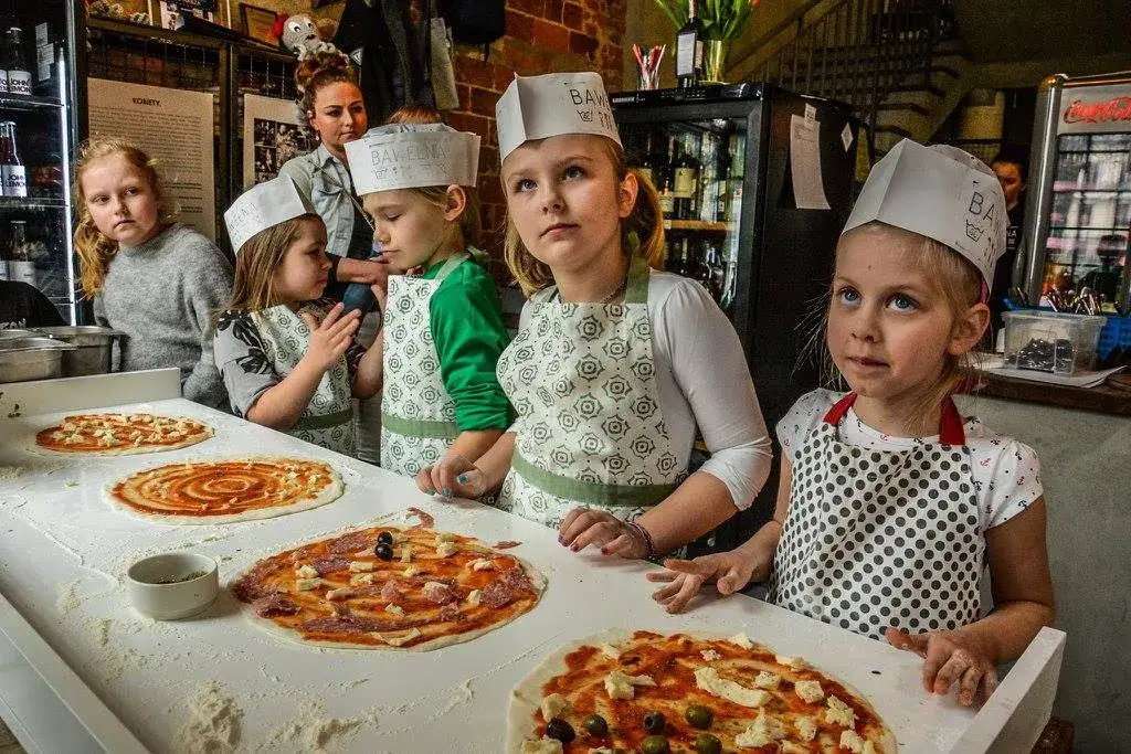 dzieci robiące pizzę na warsztatach kulinarnych