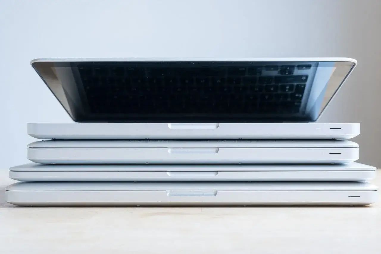 Stos białych laptopów, jeden na drugim. Górny jest lekko uchylony, ukazując klawiaturę. Zastanawiasz się, co zrobić ze starym laptopem?