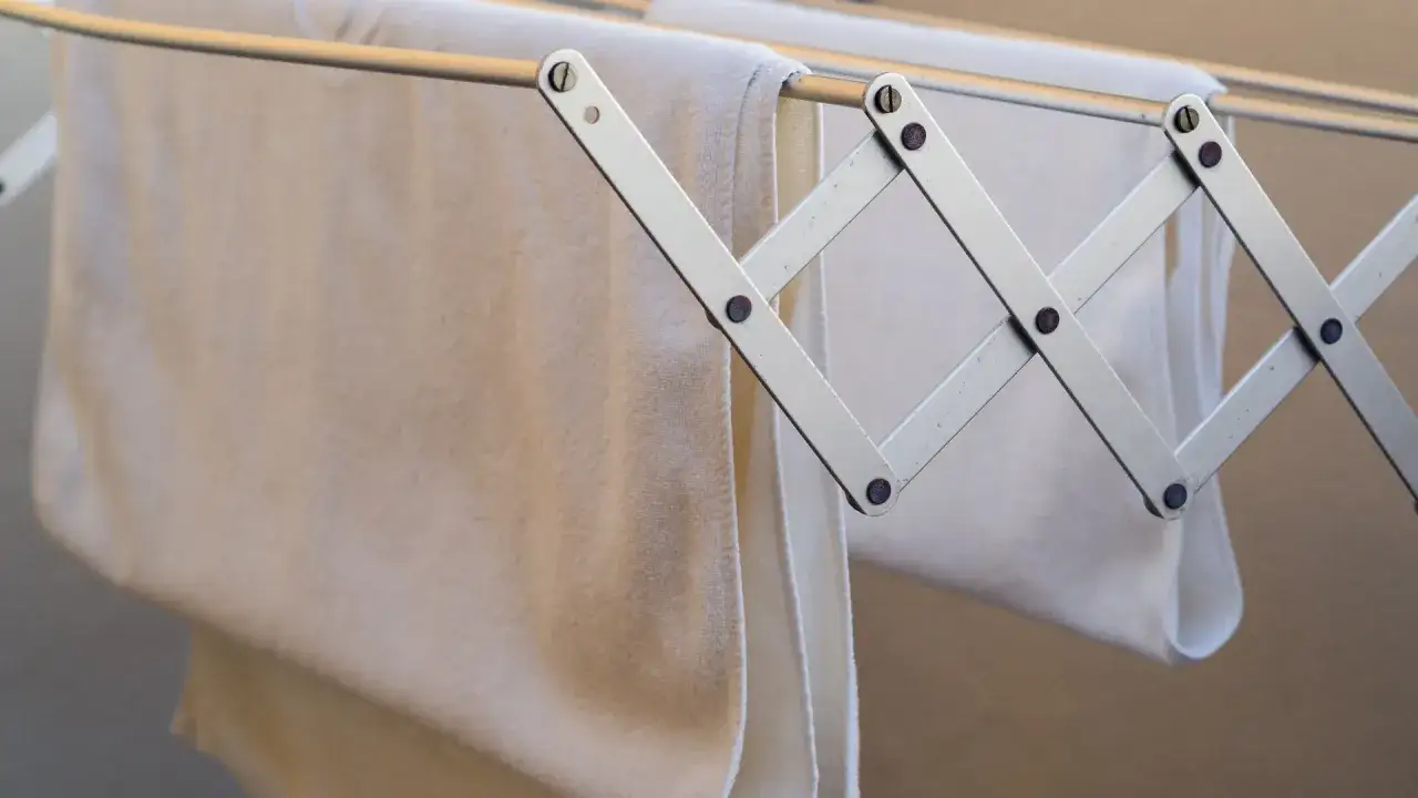 Tendedero plegable con toallas blancas colgadas, ideal para colocar en la fachada de SATE.