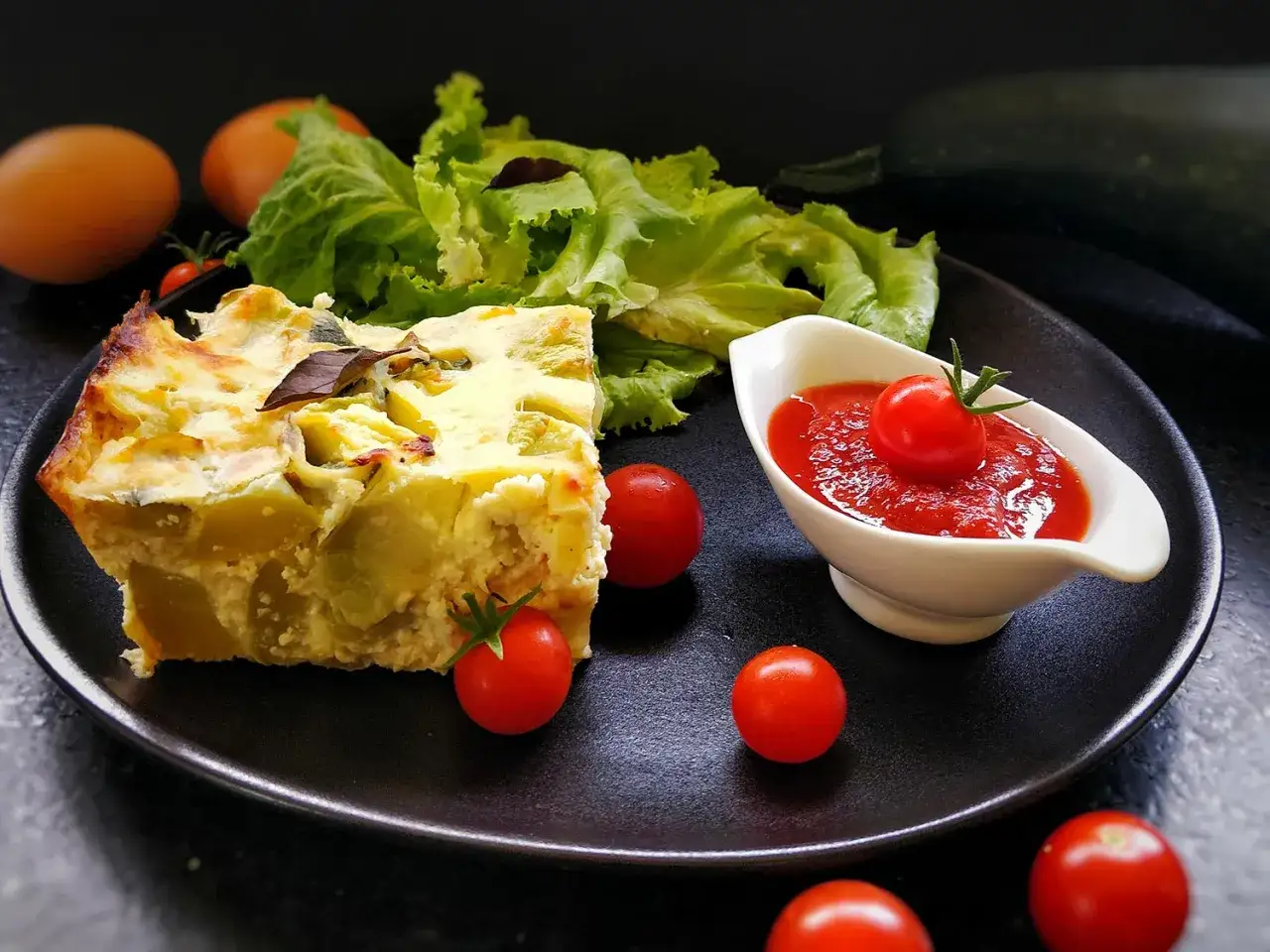 Tranche de pain de courgettes, garnie de tomates cerises, de salade verte et d'une sauce tomate.