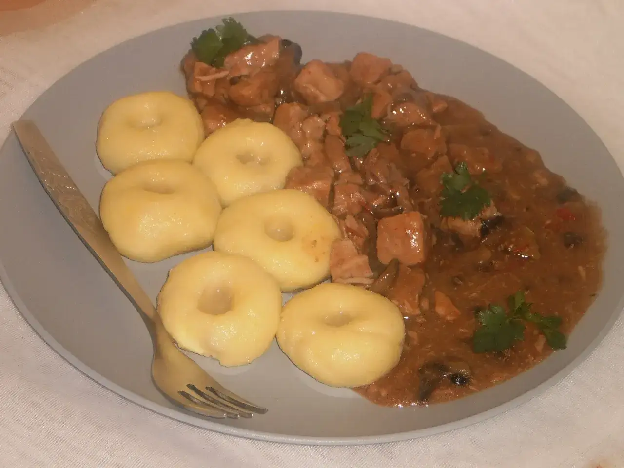 Pyszne kluski śląskie z gulaszem to idealny gnocchi przepis z czym podawać. Danie ozdobione natką pietruszki.