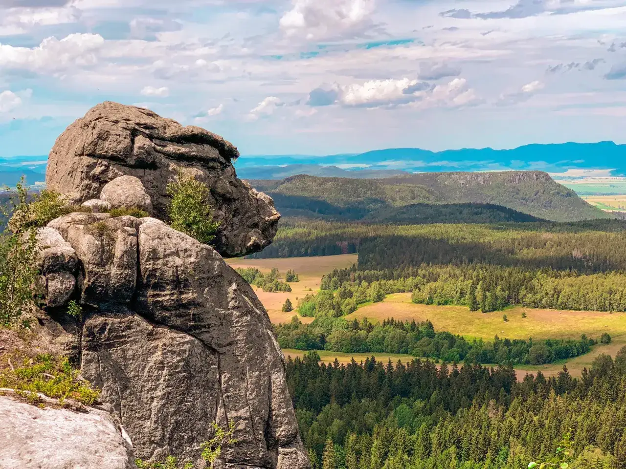 Skalny labirynt Szczeliniec Wielki wita widokiem na zielone doliny i g&oacute;ry w oddali.