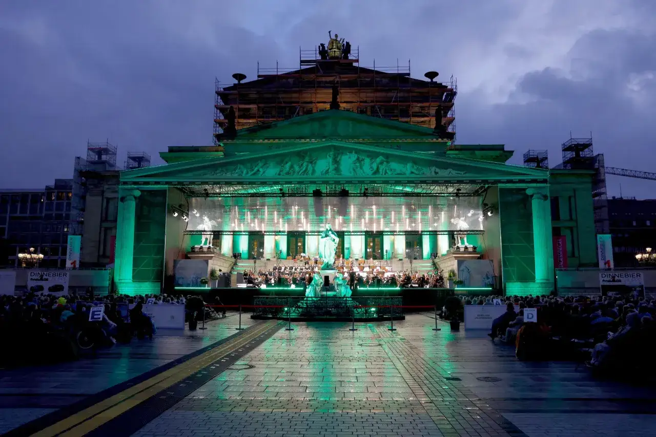Open air Berlin: Orchester spielt vor prachtvoller, gr&uuml;n beleuchteter Kulisse.