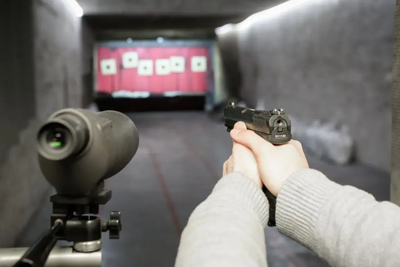 Tir &agrave; la cat&eacute;gorie C dans un stand de tir. Un pistolet est tenu en main, pr&ecirc;t &agrave; tirer sur des cibles au loin.