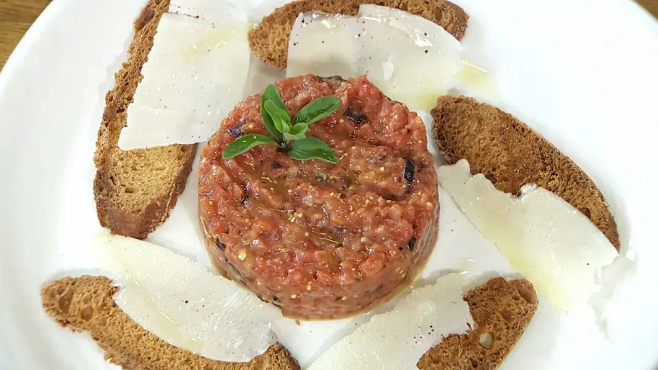 Delicioso tartar de tomate fresco, servido con finas l&aacute;minas de queso y tostadas crujientes.
